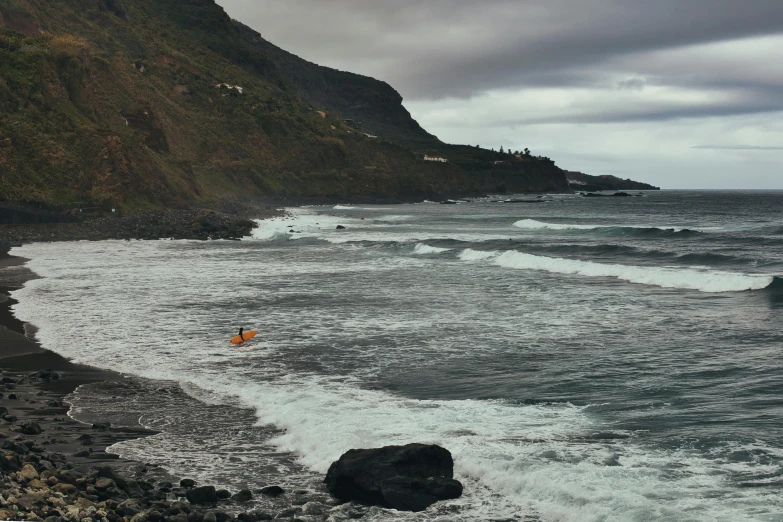 people standing on a rocky beach watching the waves crash against the cliffs