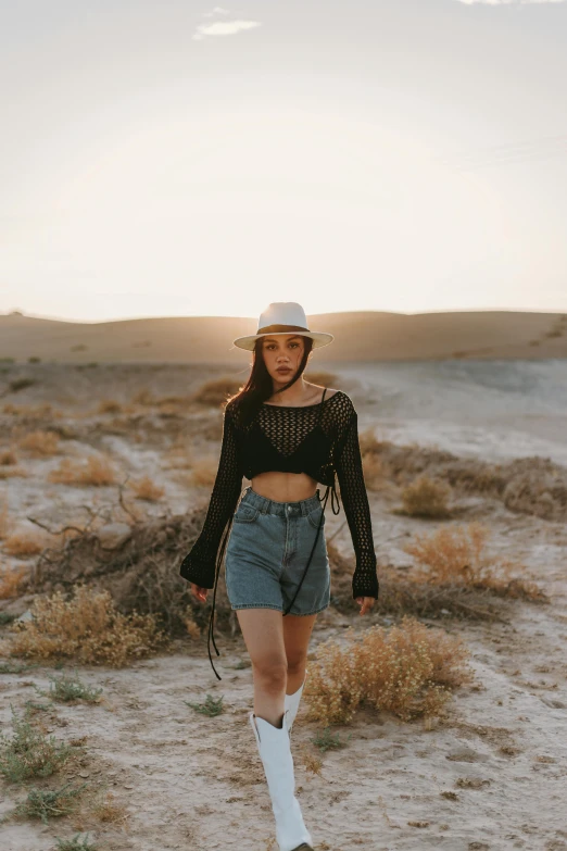 a girl wearing cowboy clothes, standing in the dirt