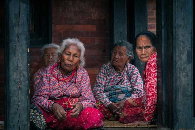 two women sitting on the floor in front of their home