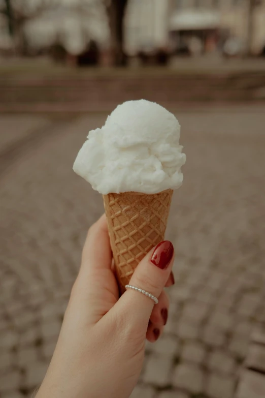 a person's hand holds an ice cream cone with a large mound