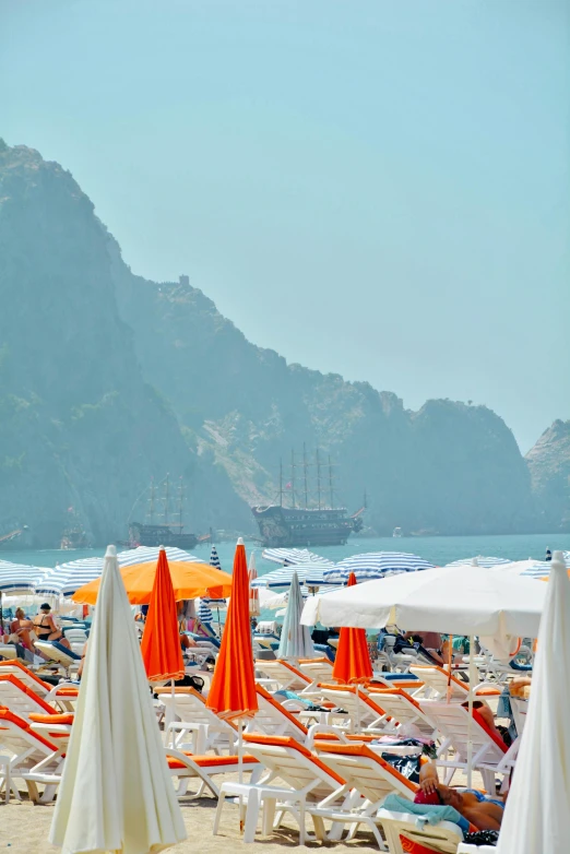 many orange and white beach umbrellas near the shore of the ocean