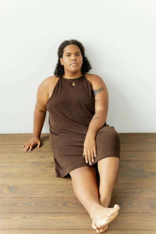 an african american woman sitting on the ground in front of a wall