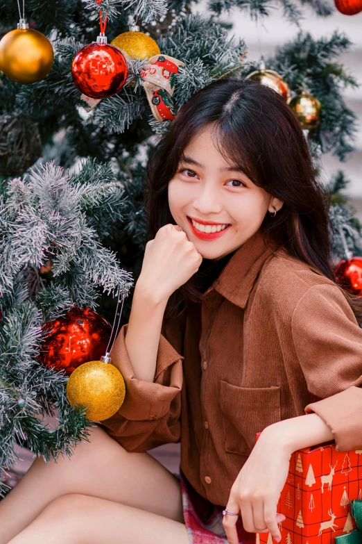 woman sitting by christmas tree with presents under christmas tree