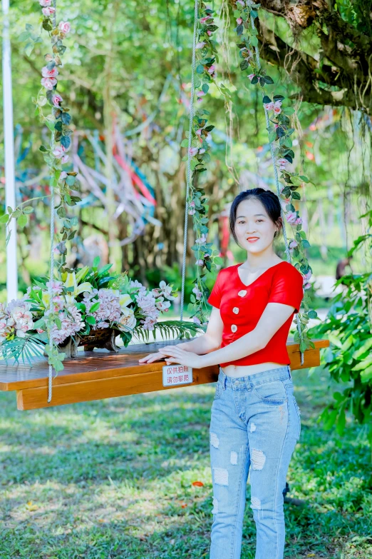 a woman holding an old piece of wood on her hand and standing under a tree with flowers