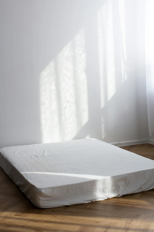 a white mattress on a wooden floor in a room