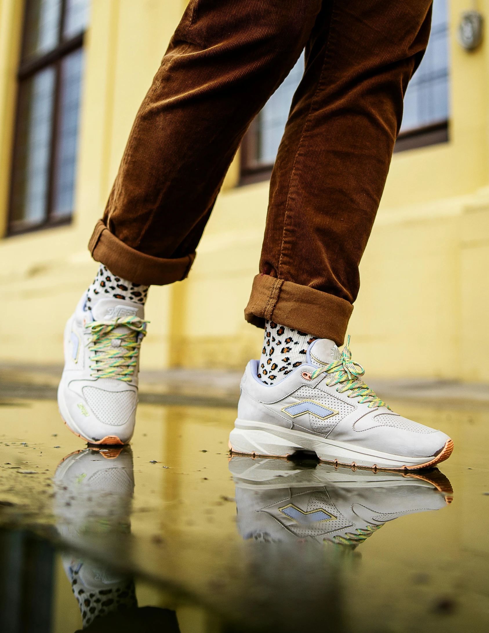 a man's legs with colorful shoes on the floor