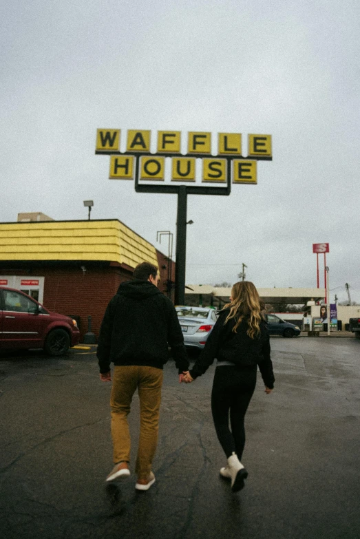 two people walking across a parking lot holding hands