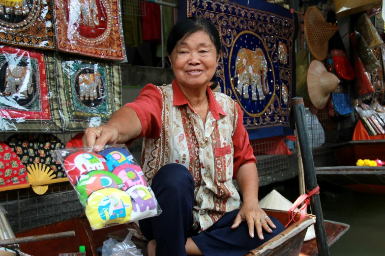 an old woman sitting in a boat selling gifts