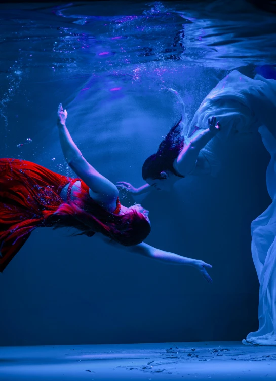 a woman in an underwater costume is diving towards another swimmer