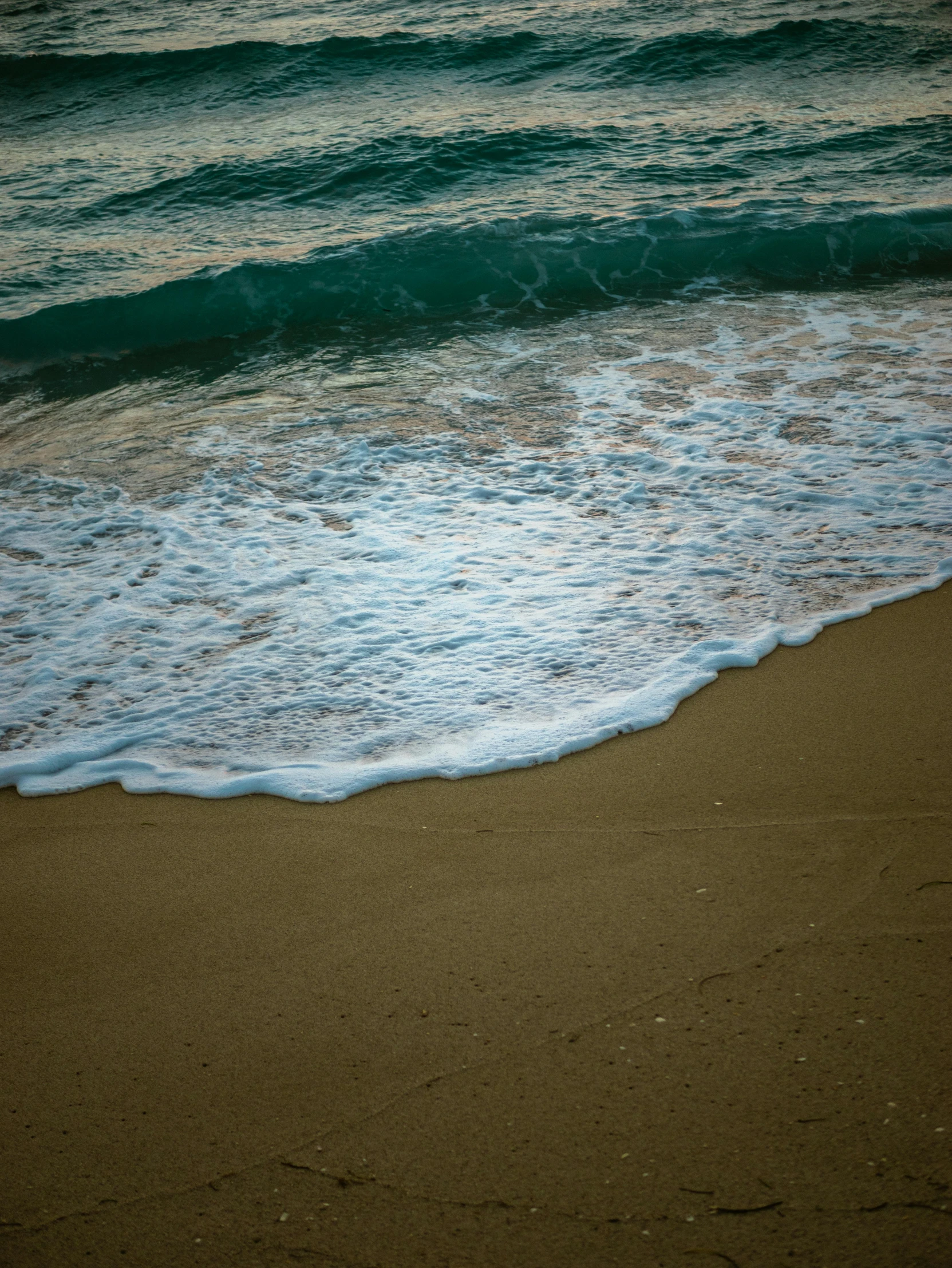 the sand and water on a beach with waves