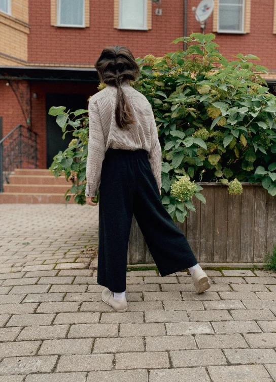 a woman walking down a sidewalk with a house in the background