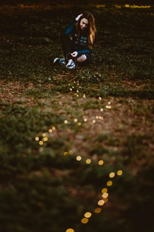 a woman kneeling in the grass on top of a grass covered ground