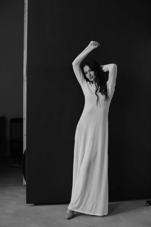 woman in white dress standing next to wall