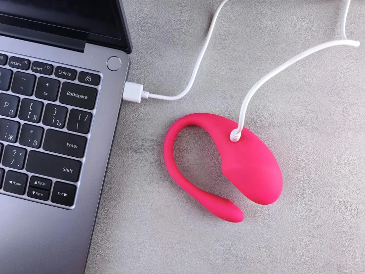 a laptop sits on the floor next to a phone, headphones, and other items