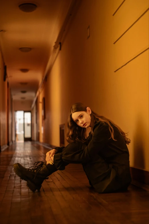a woman sitting on the floor in a hall wearing boots