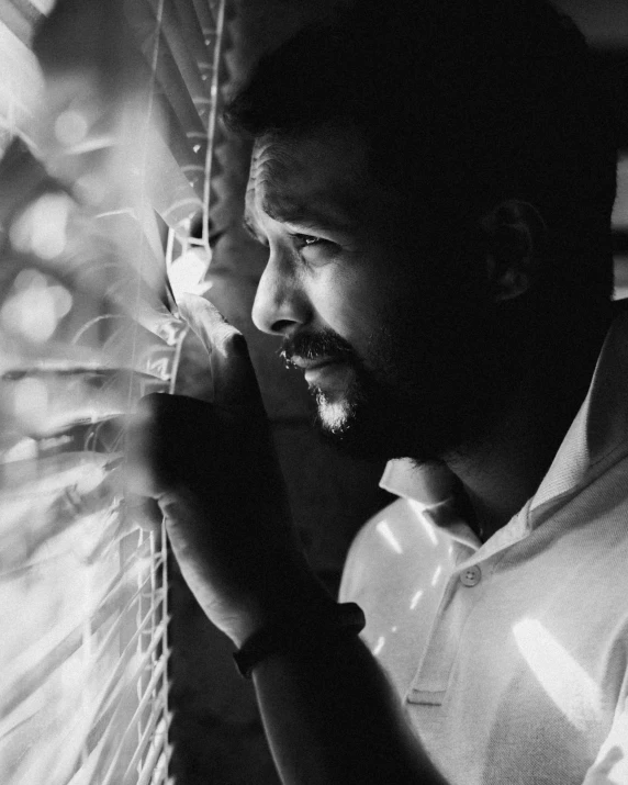 man looking out through blinds in his house