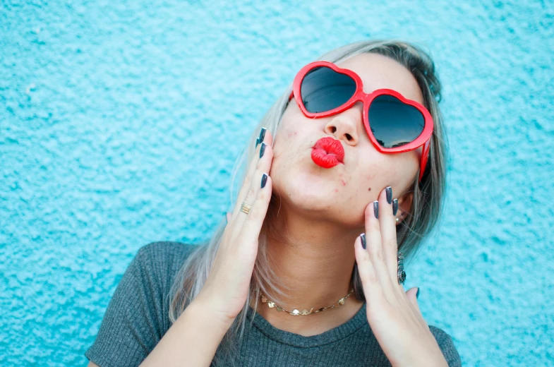 a woman wearing sunglasses with her tongue out while laying on the ground