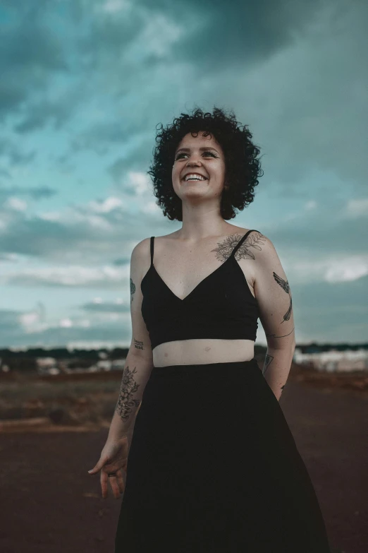 a woman wearing black dress standing outside under the blue sky