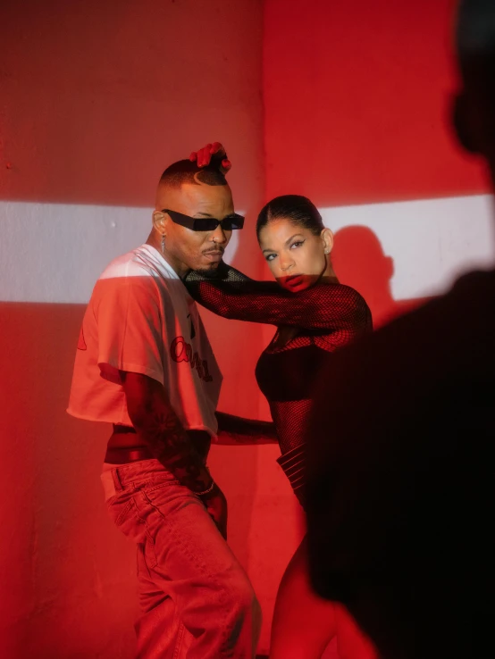 two people wearing red pose in front of a red backdrop