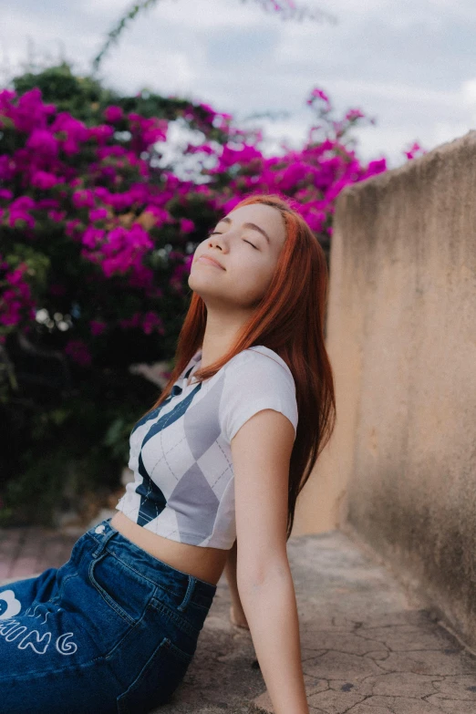 red haired woman sitting in front of purple flowers