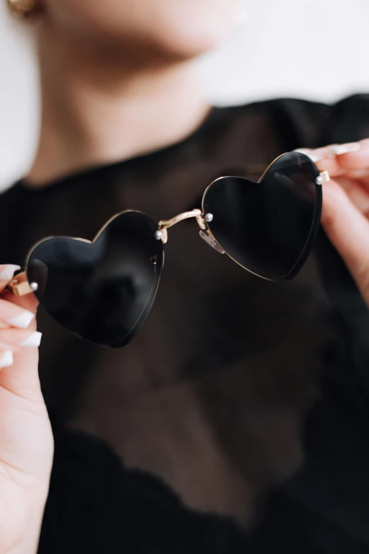 a woman is wearing heart shaped sunglasses that have black frames