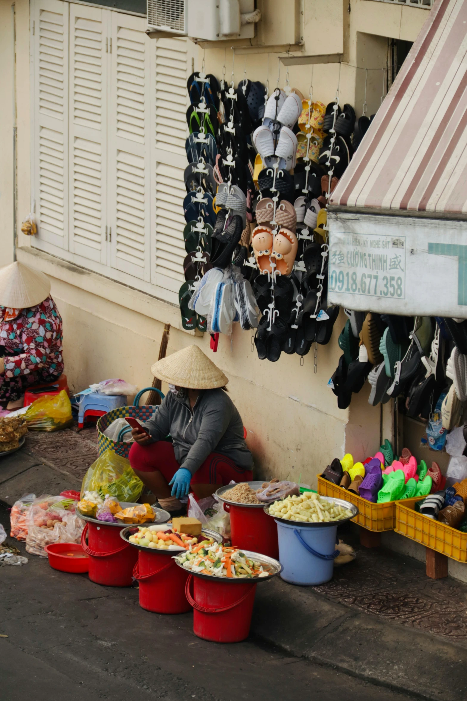 a vendor with her hat on sits near a table full of bowls of food