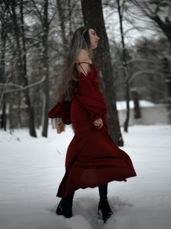 a woman dressed in red is walking through the snow