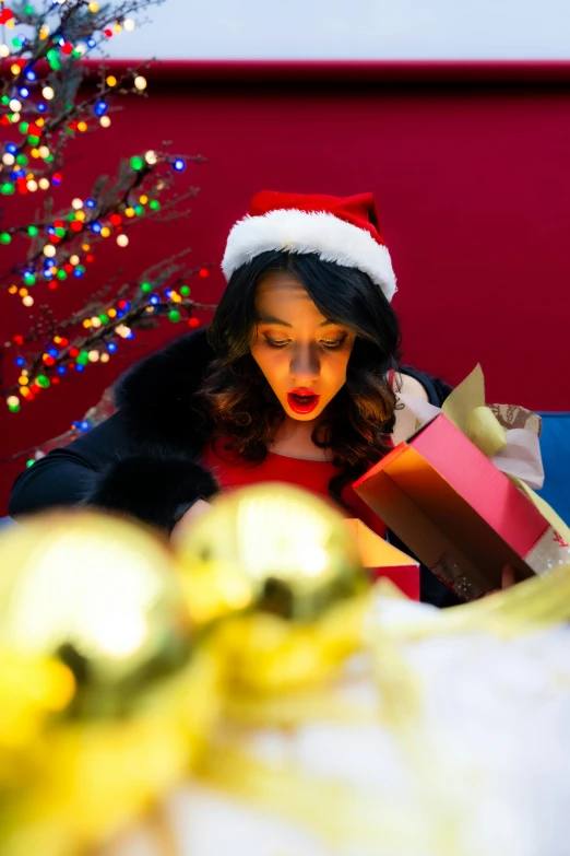 a woman in a santa hat opening a christmas presents
