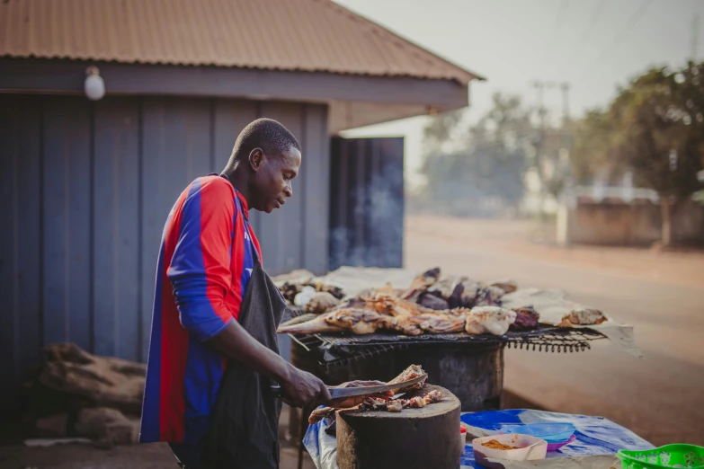 the man is preparing food on the grill on a  day