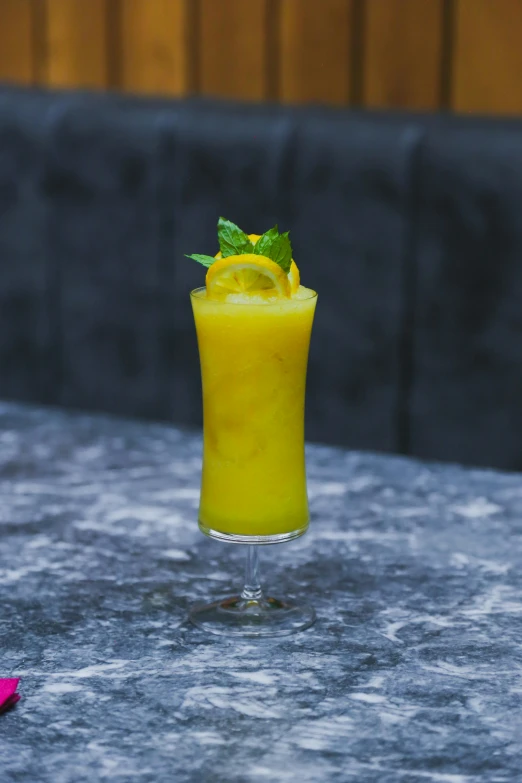 a yellow drink garnished with mint on the outside patio