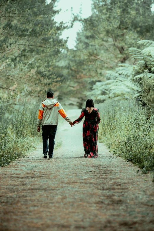 a man and woman holding hands on a dirt road