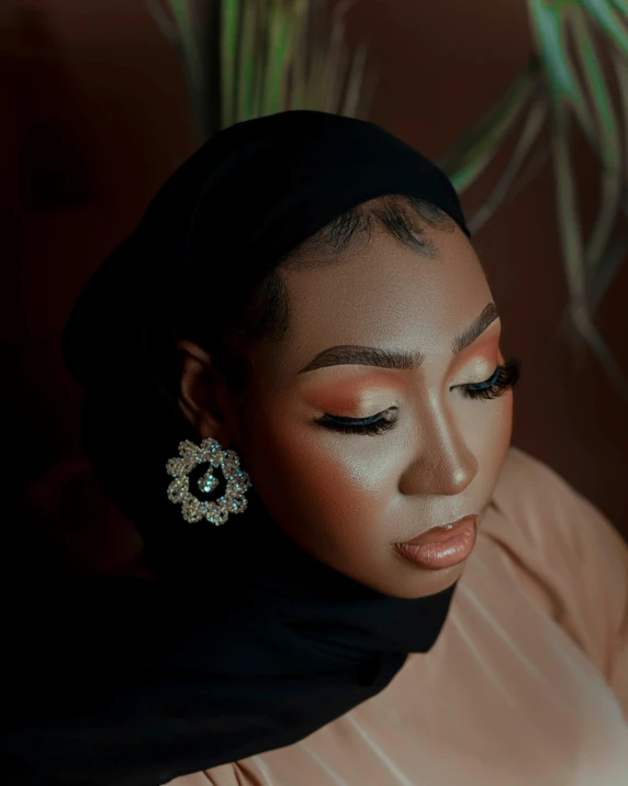 woman with golden makeup with green earrings