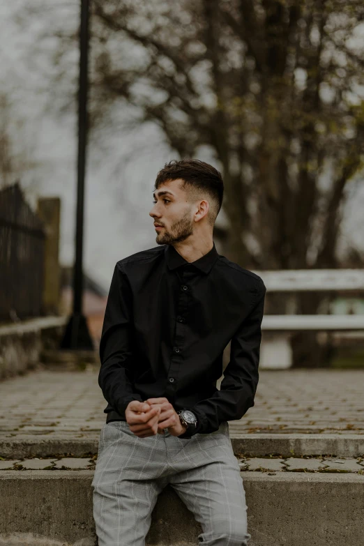 man in black shirt and gray pants sitting on steps