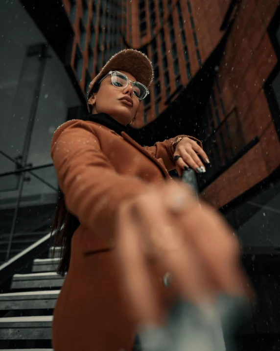 a young woman in brown jacket and hat taking pictures in snow