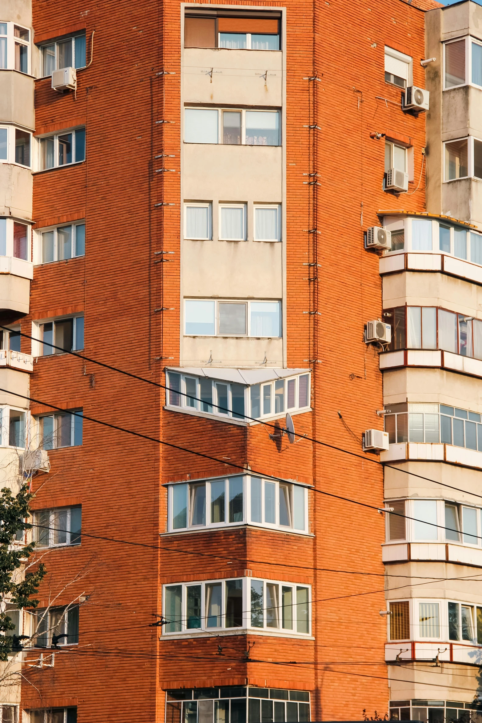 a bus drives past tall orange buildings with balconies