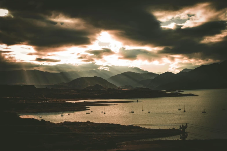 sunset in a mountainous area with several boats on the water