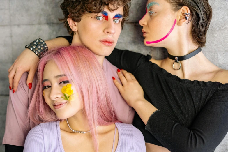 three people posing for the camera, one has pink hair