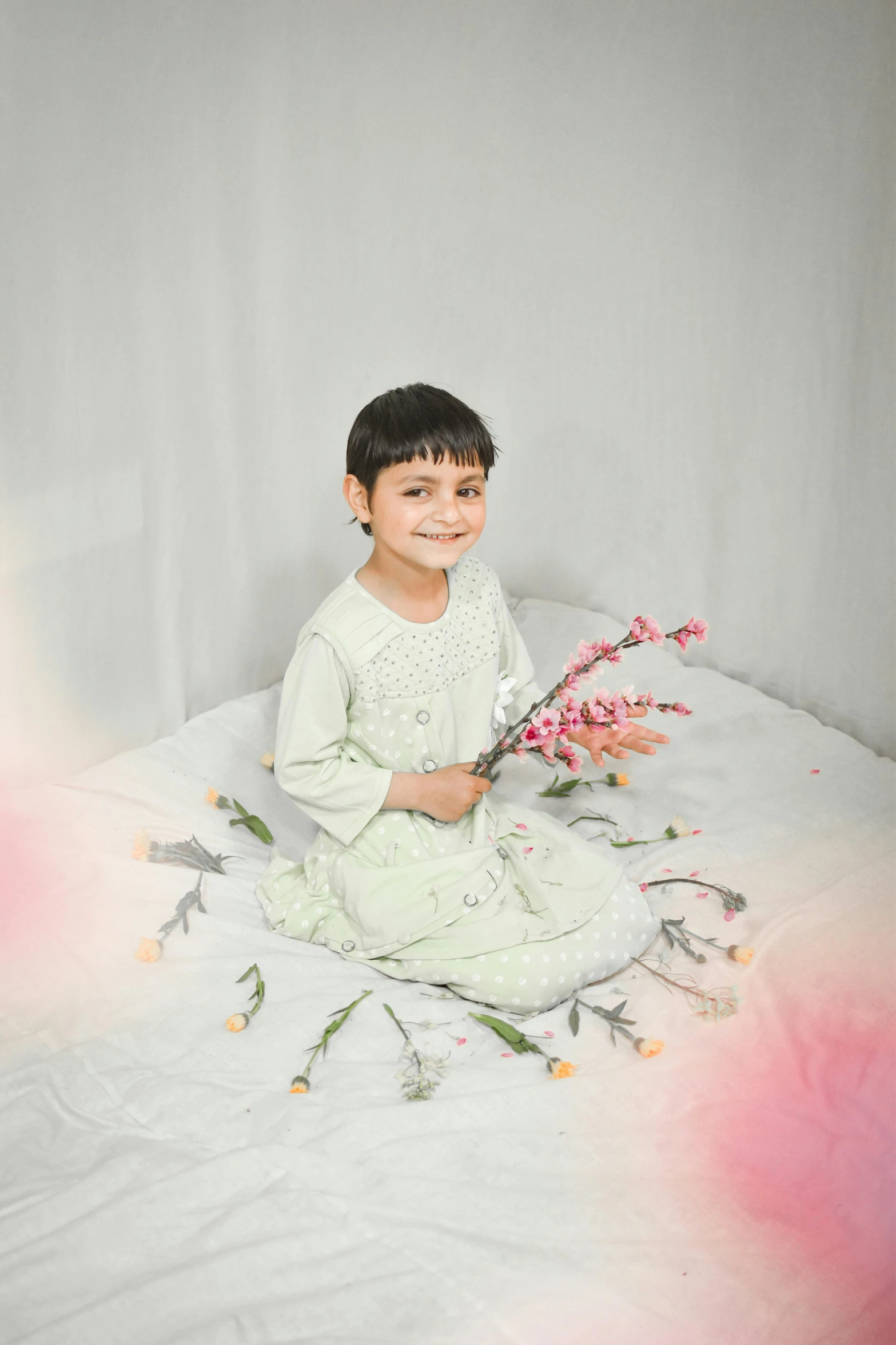 a little boy sitting on a bed with flowers on his feet