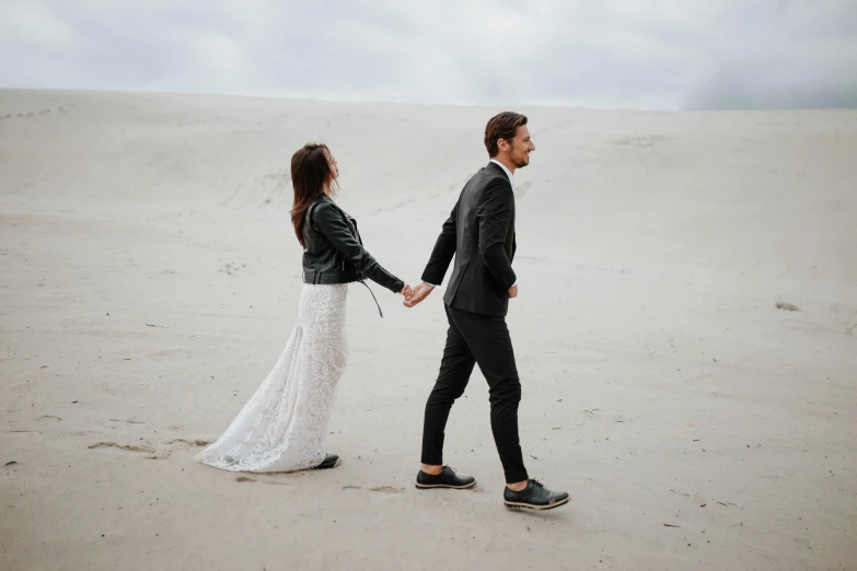 a bride and groom walking in the sand at white sands