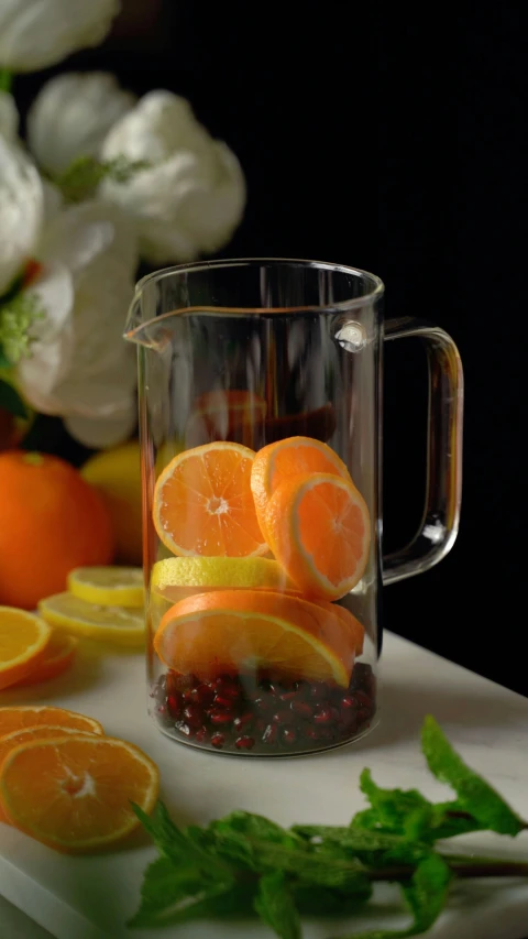 a pitcher filled with liquid and slices of oranges