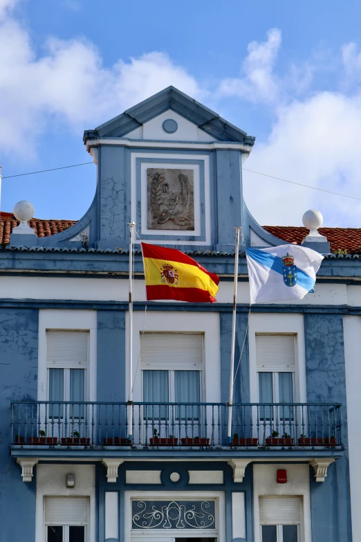 flags flying in front of an old building on a cloudy day