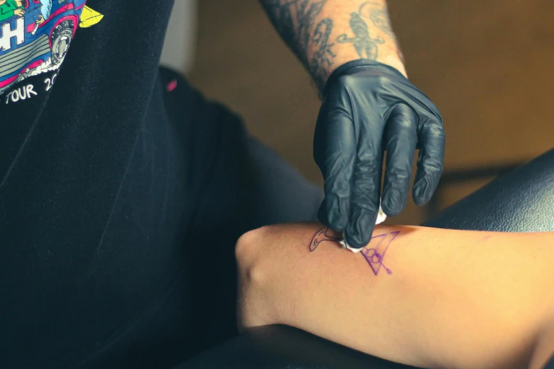 an arm tattoo being done by someone's hand