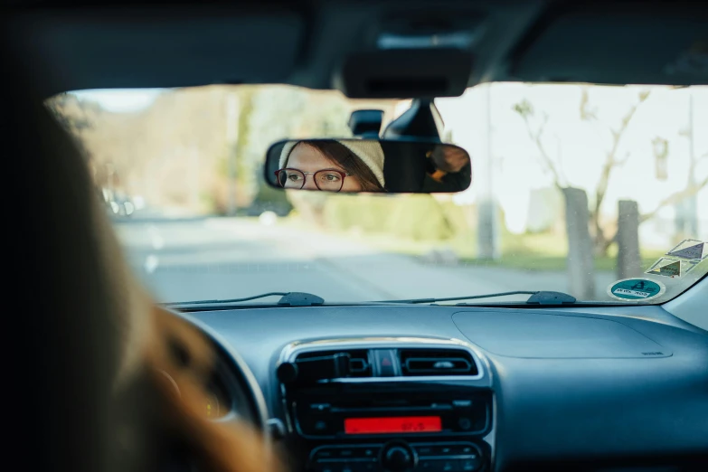 person driving down a street wearing glasses in a car