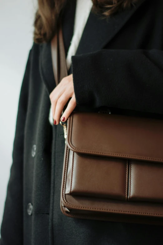 a person in a coat holding a brown bag