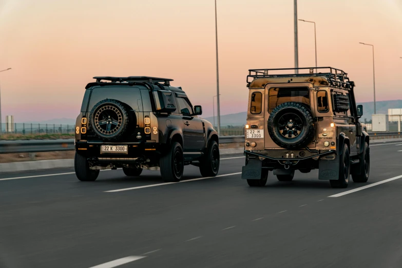 two army vehicles drive down a highway in front of each other