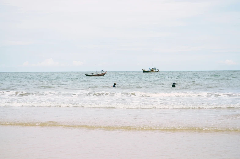 people swimming in the ocean with boats floating in the water