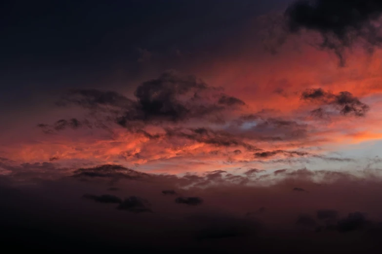 a plane flying into an orange and red sunset