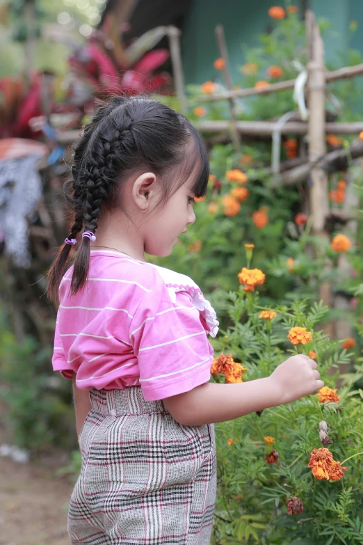 a little girl in a pink top picking flowers