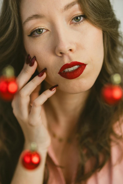 a woman with red lipstick holds christmas ornaments