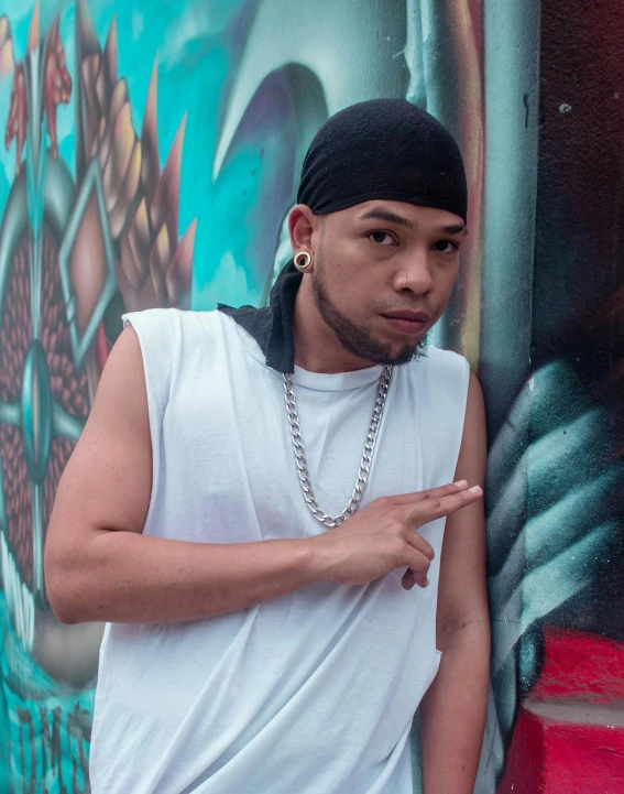 a young man standing next to a graffiti wall